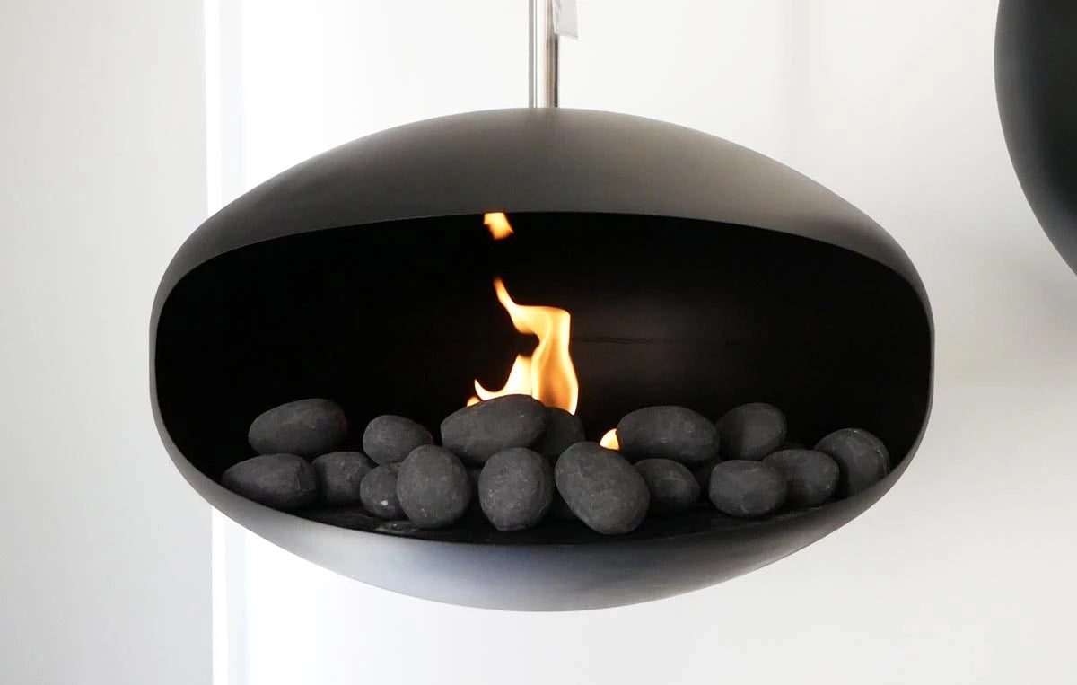 Modern bio fireplace featuring black ceramic pebbles and flickering flames, creating a stylish focal point.