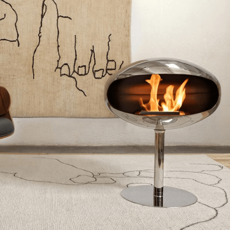 Cocoon Pedestal polished steel bioethanol fireplace with flames, modern design in a stylish home setting.