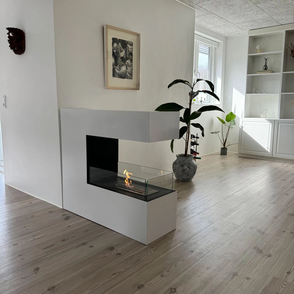 Large white powder-coated freestanding bioethanol fireplace with glass viewing panel in a modern living room.
