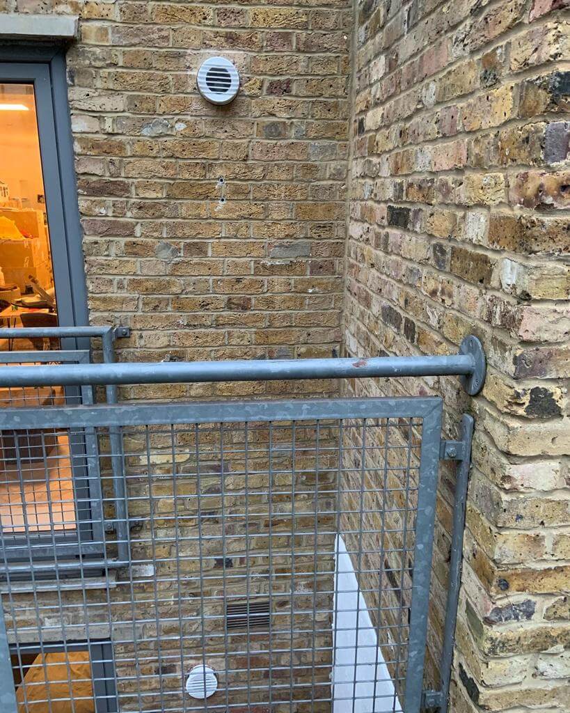 Close-up view of a brick wall with a heat recovery ventilator installed, showcasing modern ventilation design.
