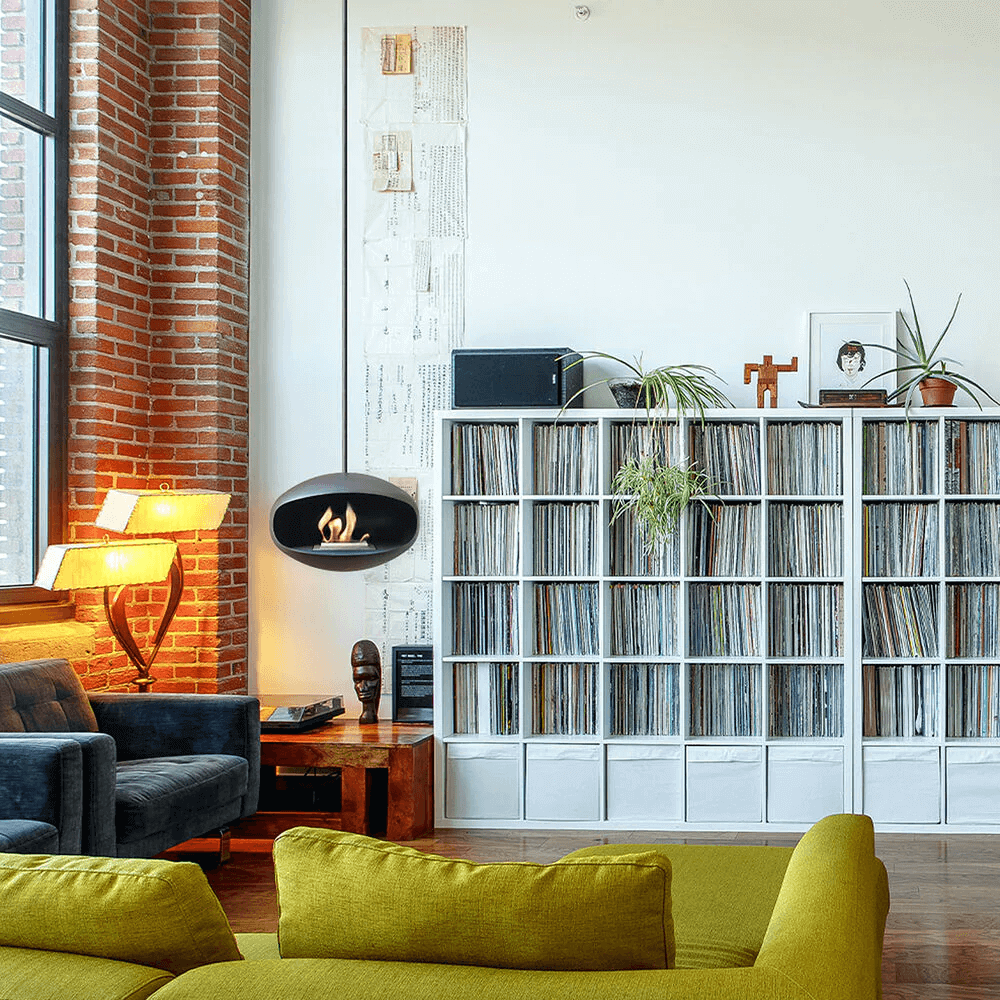 Cocoon Aeris matte black bioethanol fireplace mounted in a modern living room with vinyl record storage.