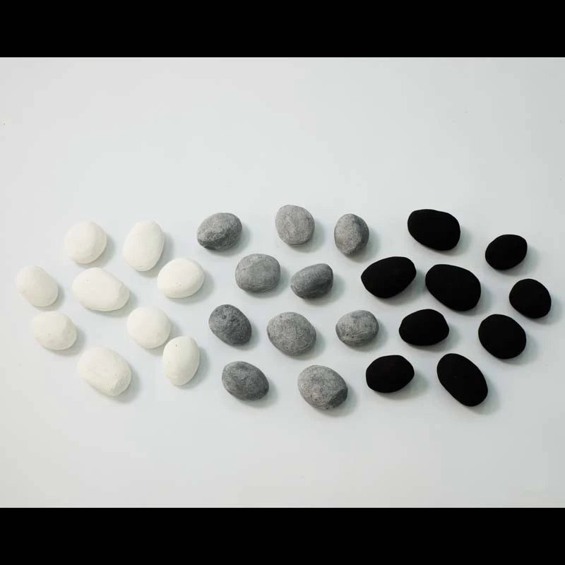 Decorative ceramic pebbles in white, grey, and black colors arranged creatively on a flat surface.