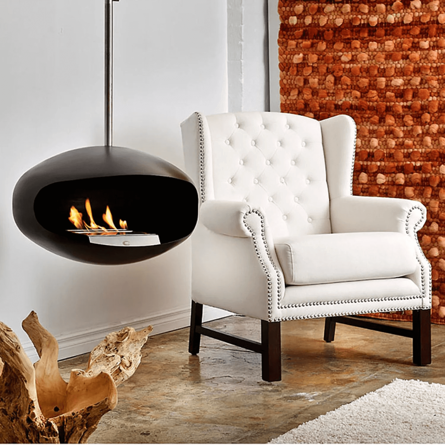 Cocoon Aeris black bioethanol fireplace hanging above a white armchair in a modern living space.