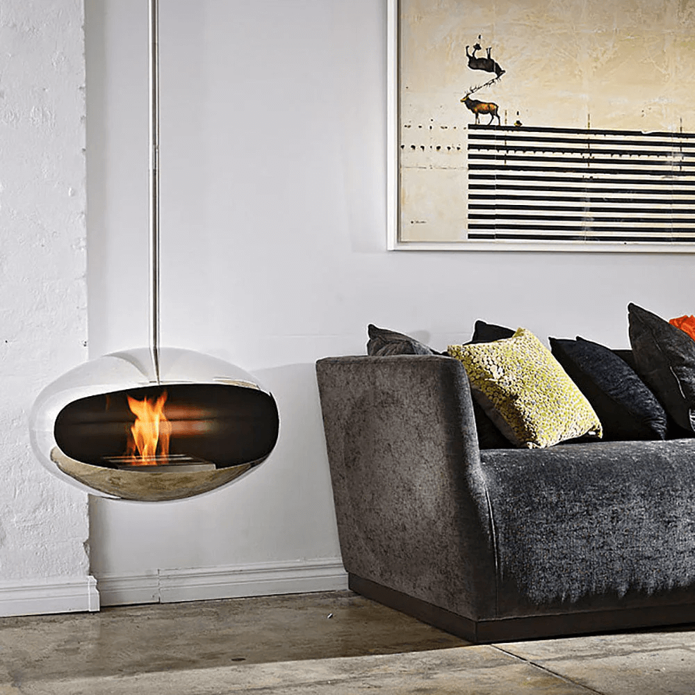 Cocoon Aeris modern bioethanol fireplace in stainless steel, suspended above a stylish sofa in a contemporary living room.