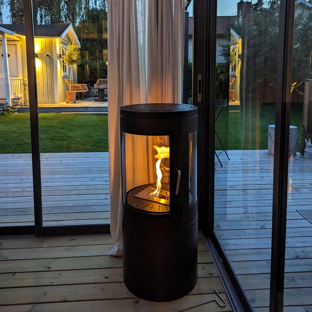 Columbus bioethanol stove with 360-degree view, showcasing flames through curved glass panels in a modern setting.