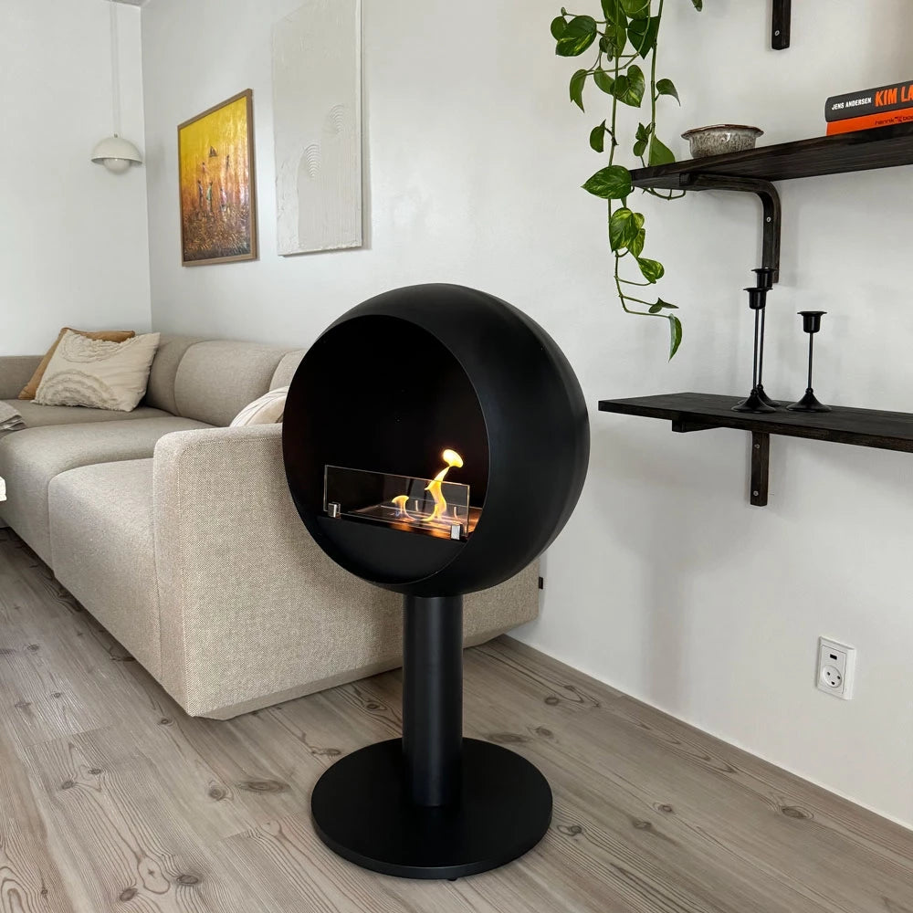 Edmonton freestanding bioethanol fireplace in a modern living room, showcasing its sleek black round design and vibrant flames.