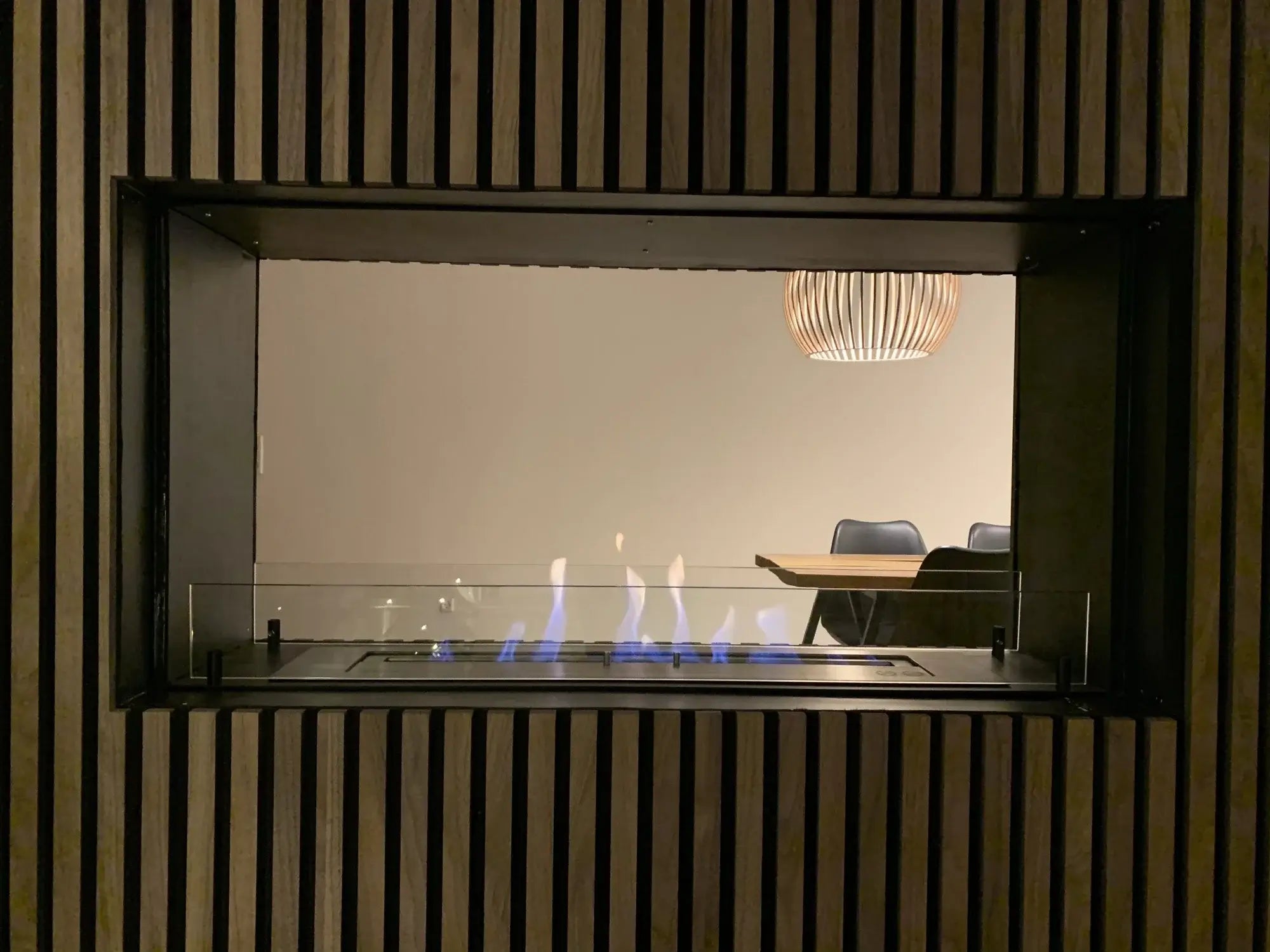 Modern bioethanol fireplace insert featuring flames behind glass panels in a sleek interior.