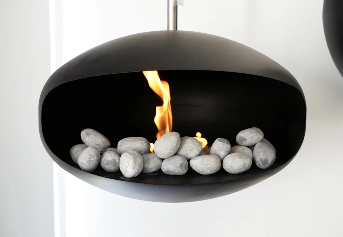 Modern bio fireplace with grey ceramic pebbles and a flame, creating a stylish decorative feature.