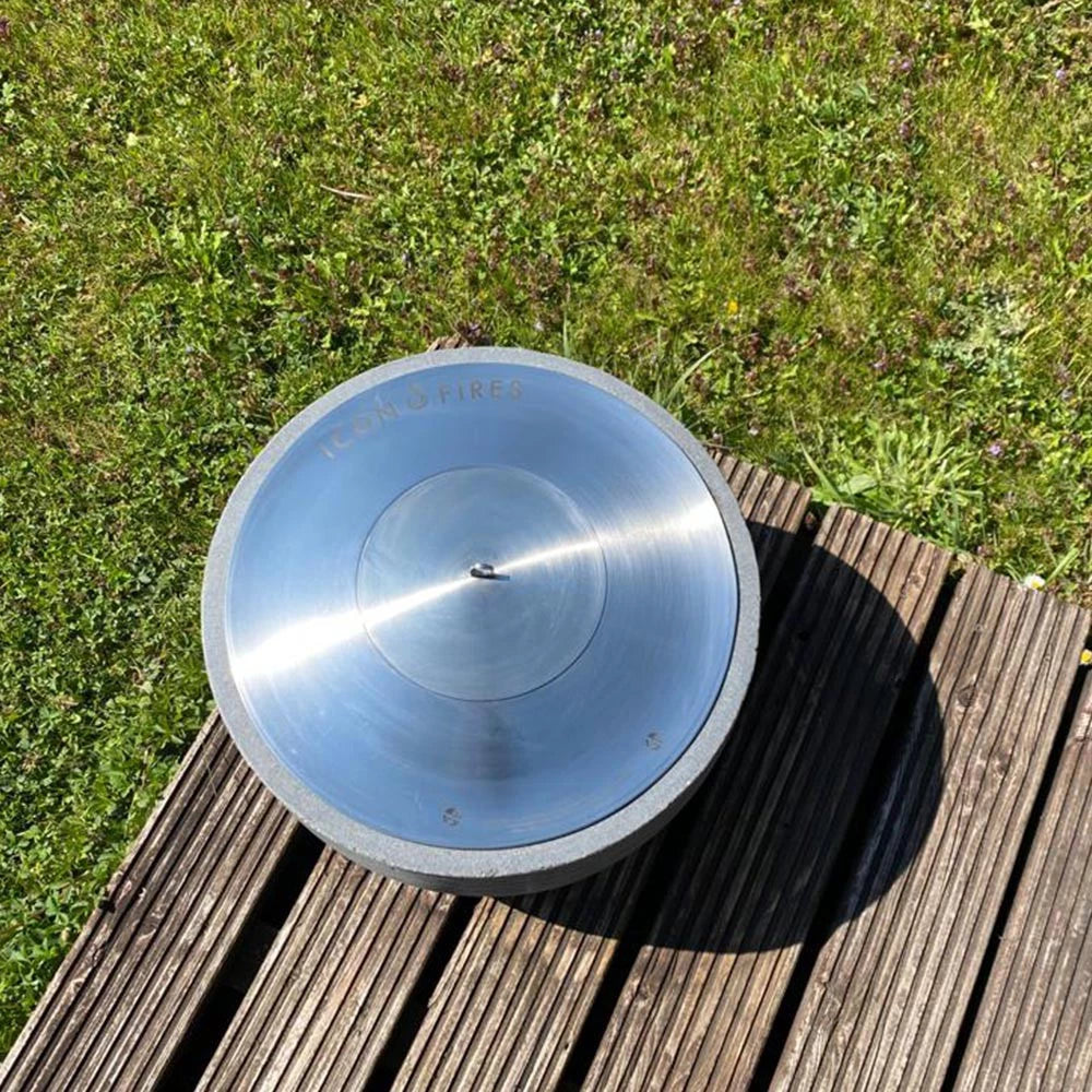 Icon Fires round bioethanol burner RD380 in stainless steel on a wooden deck surrounded by grass.