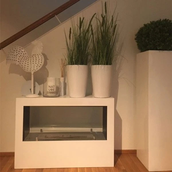 Modern white bioethanol fireplace table with decorative plants and accessories, ideal for home decor.