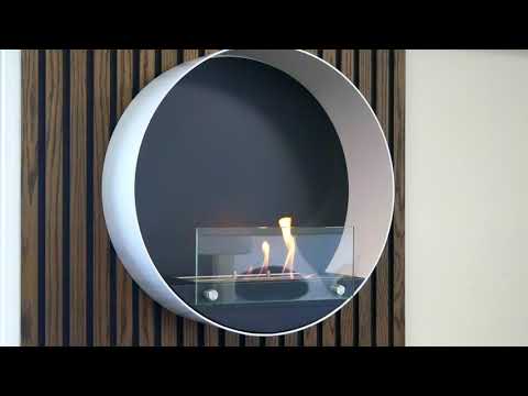 Contemporary round white wall mounted bioethanol fireplace with visible flames and contrasting black background.